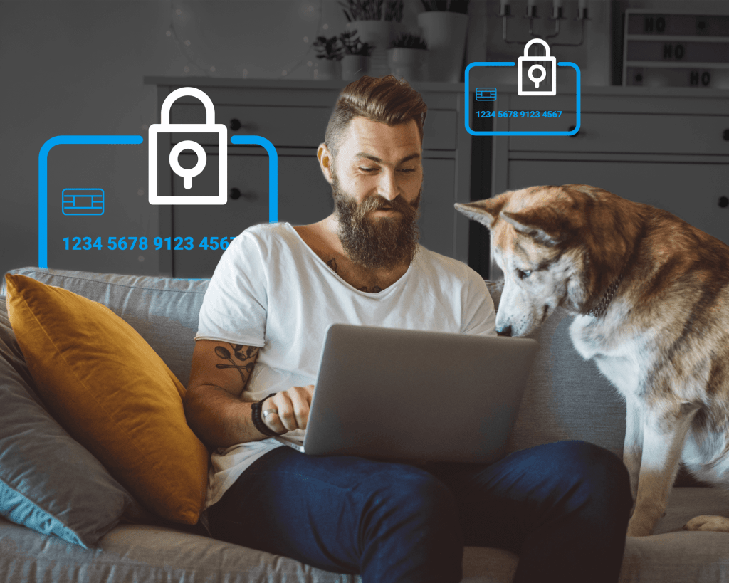 Um jovem senta-se num sofá a olhar para um computador enquanto o seu cão o observa ao seu lado. Ícones de cartões de crédito seguros aparecem em segundo plano atrás dele.